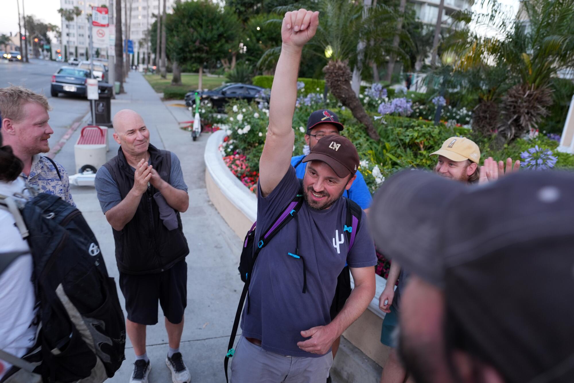 A man raises his fist in the air as a group around him smiles and claps.