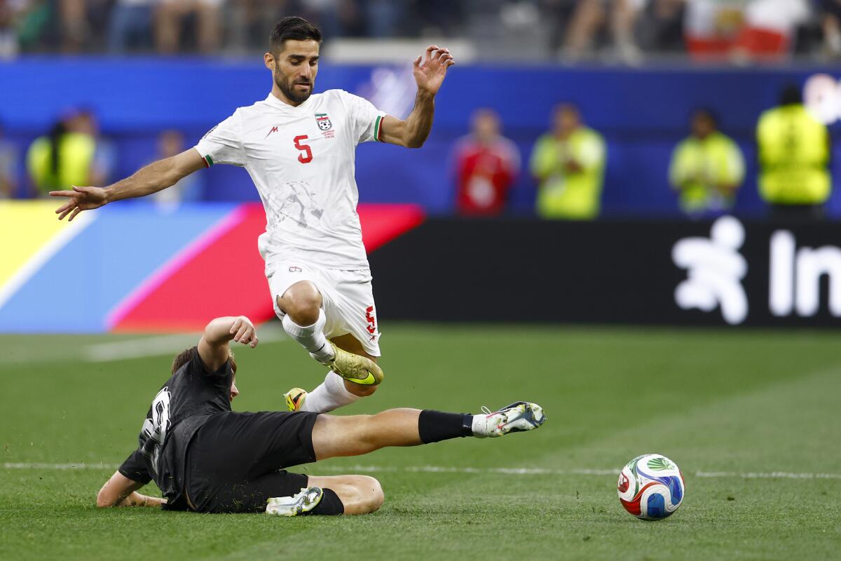 Iran defender Milad Mohammadi leaps over a New Zealand defender during the second half.