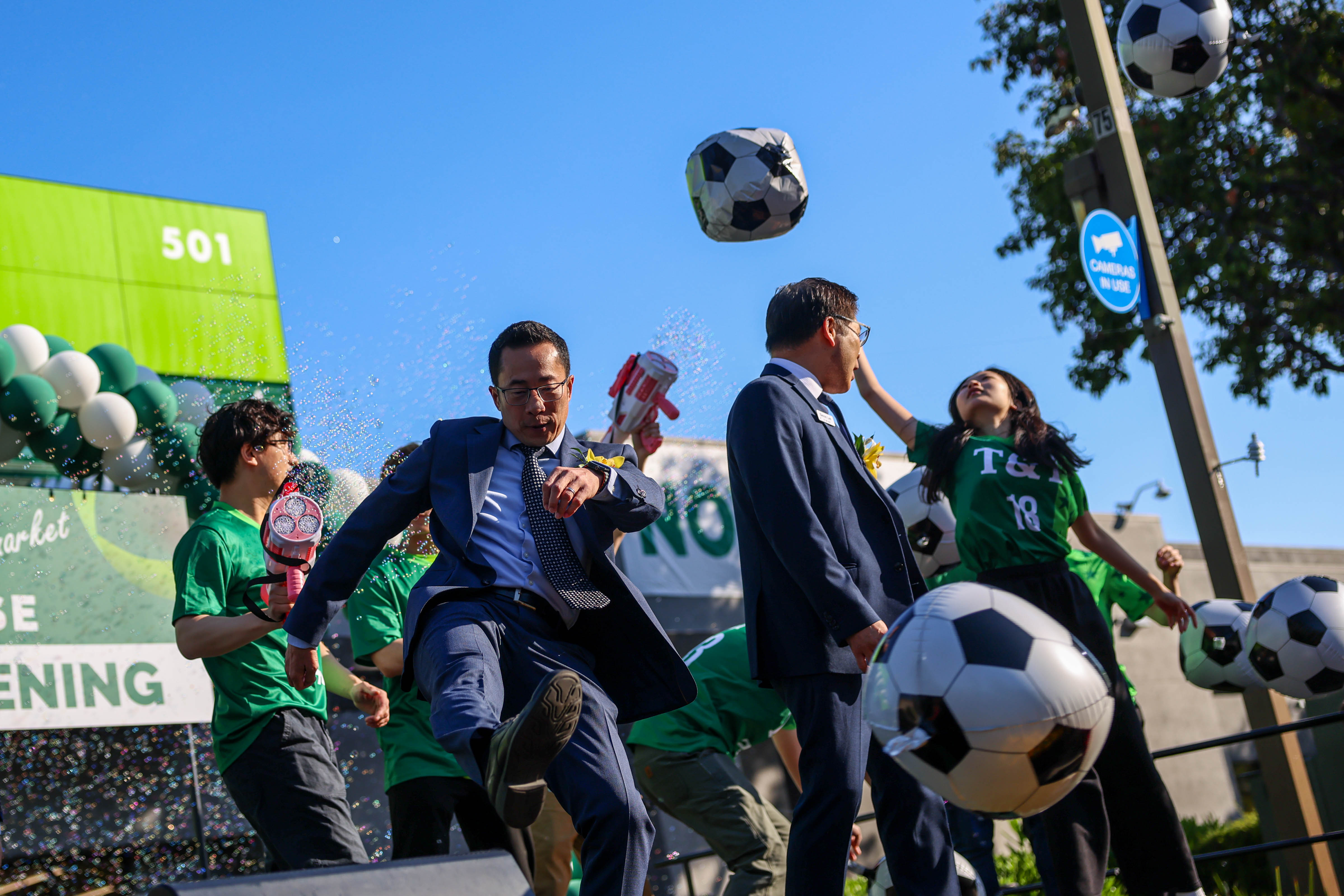 Businessmen with T&T Market throw soccer balls into the crowd...