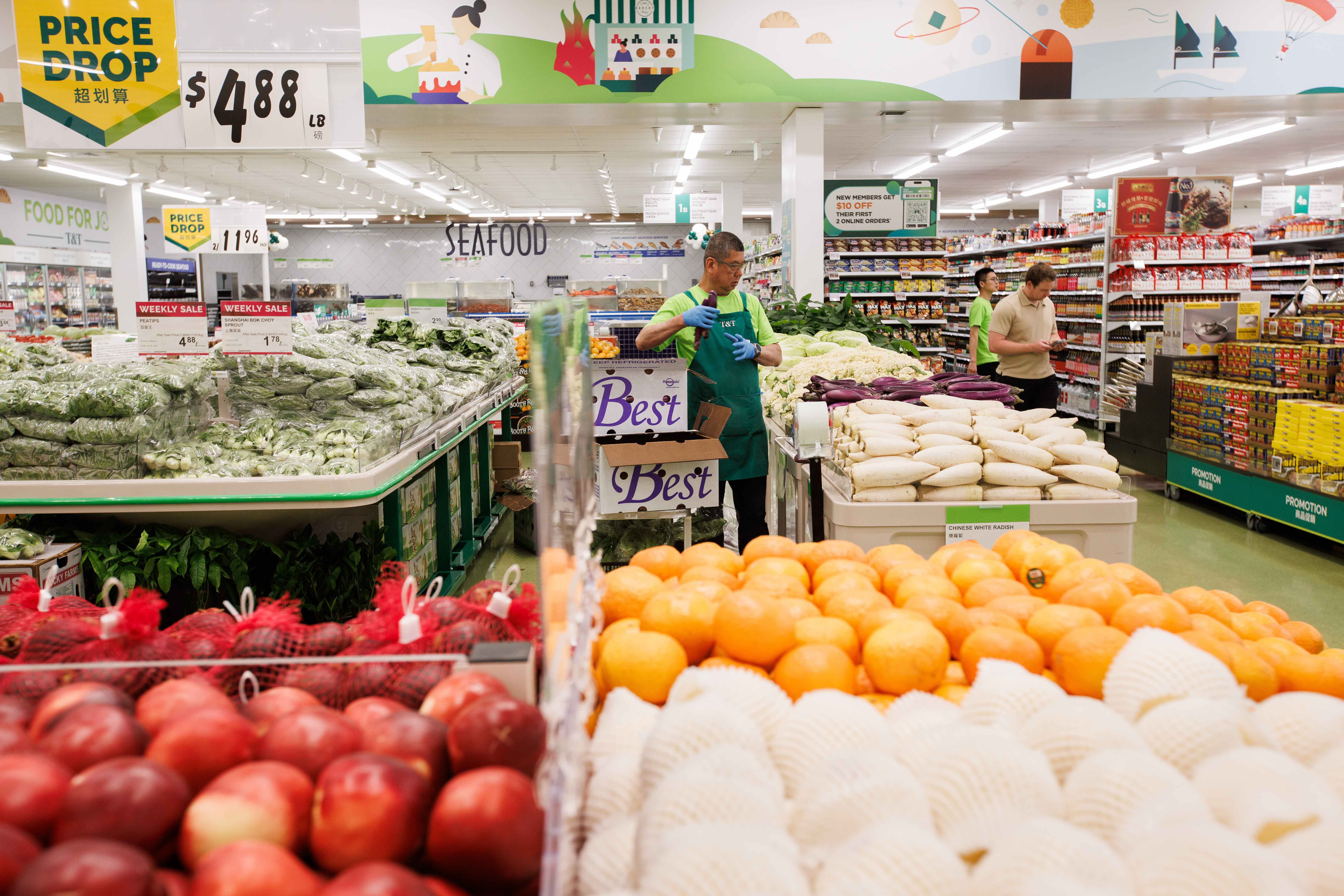 An employee stocks vegetables in the produce section ahead of...