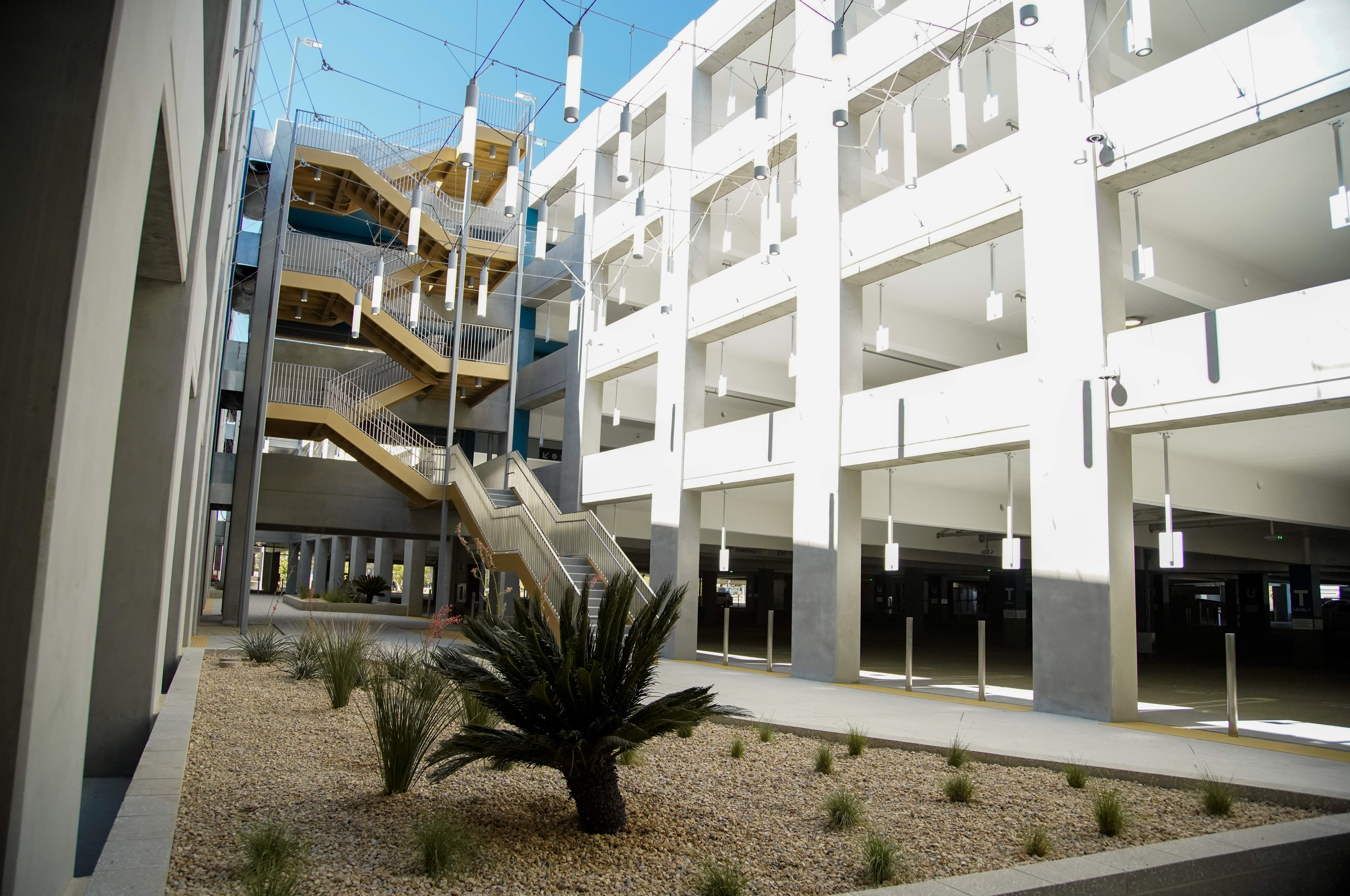 A walkway and stairs and hanging lights between the parking...