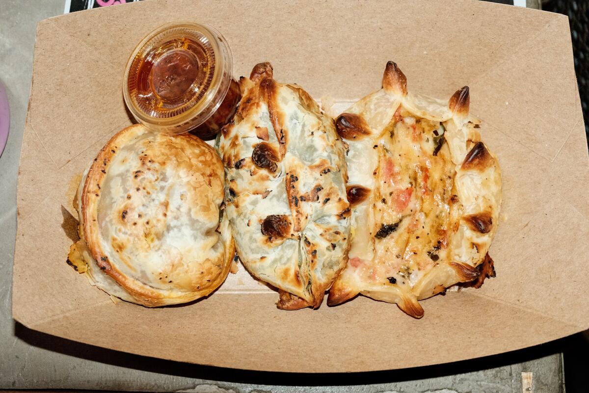 A trio of Argentinian empanadas in a cardboard tray