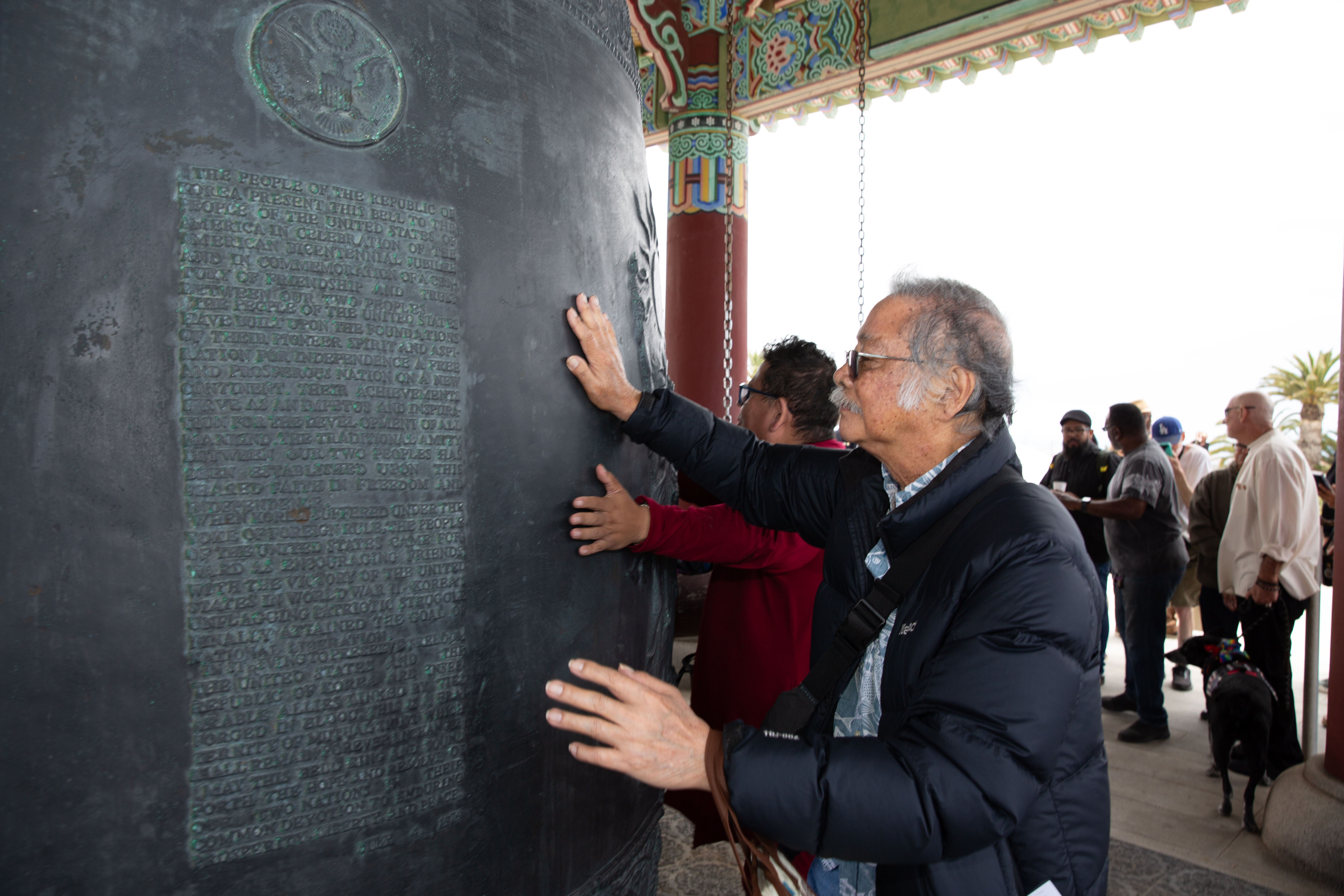 Officials and guests feel the reverberations of a ringing bell...