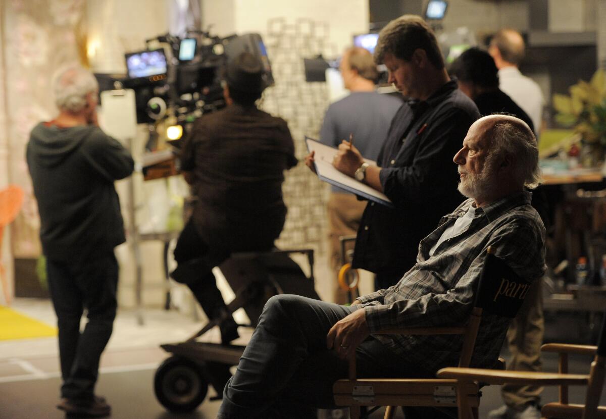 James Burrows sits in a director's chair on set.