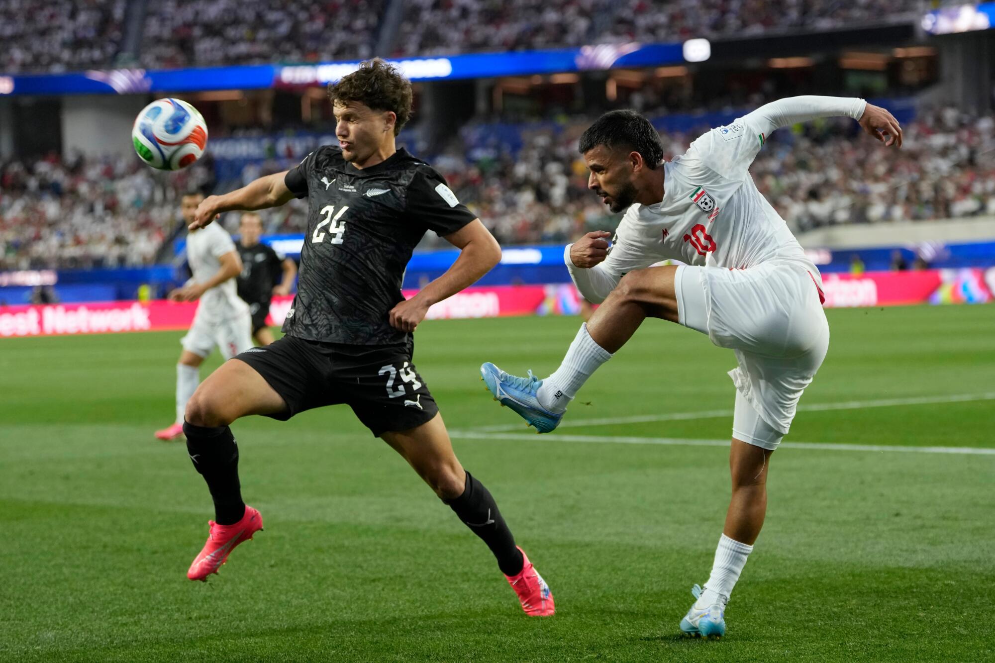 New Zealand's Callan Elliot, left, and Iran's Mehdi Ghayedi battle for the ball during a World Cup Group G match.