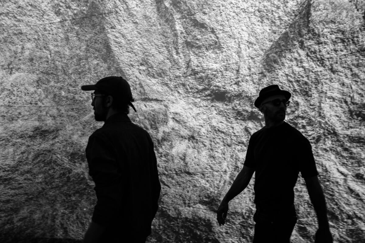 Men walk inside a cave-like space. 