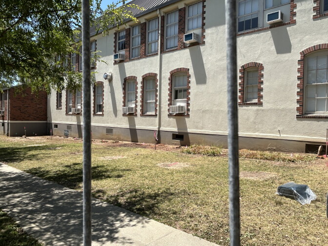 A white school building with grass in foreground. 