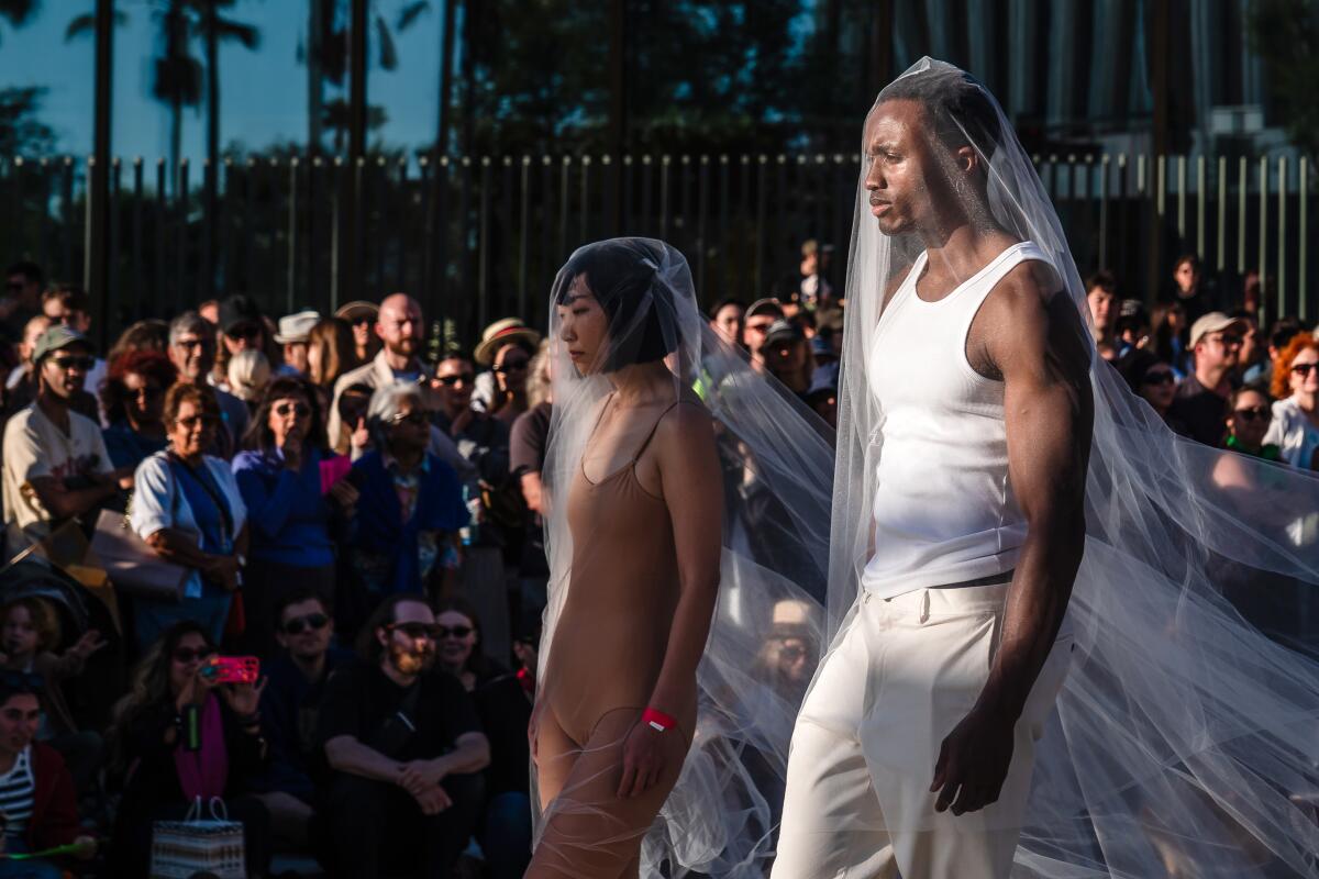 A man and woman wearing tulle over them walk in the parade.