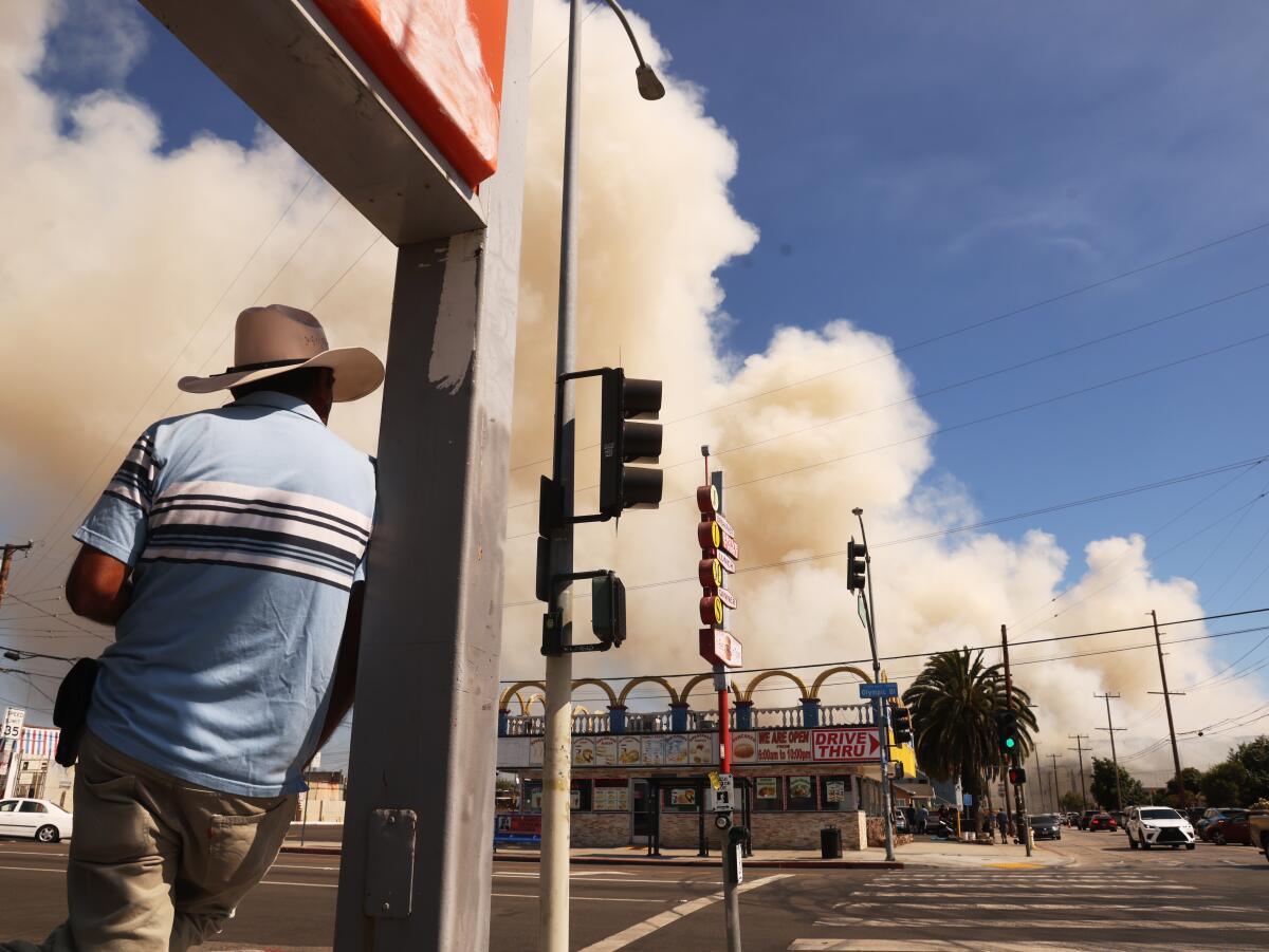 Boyle Heights residents keep a watchful eye on the fire at a warehouse that continues to burn.