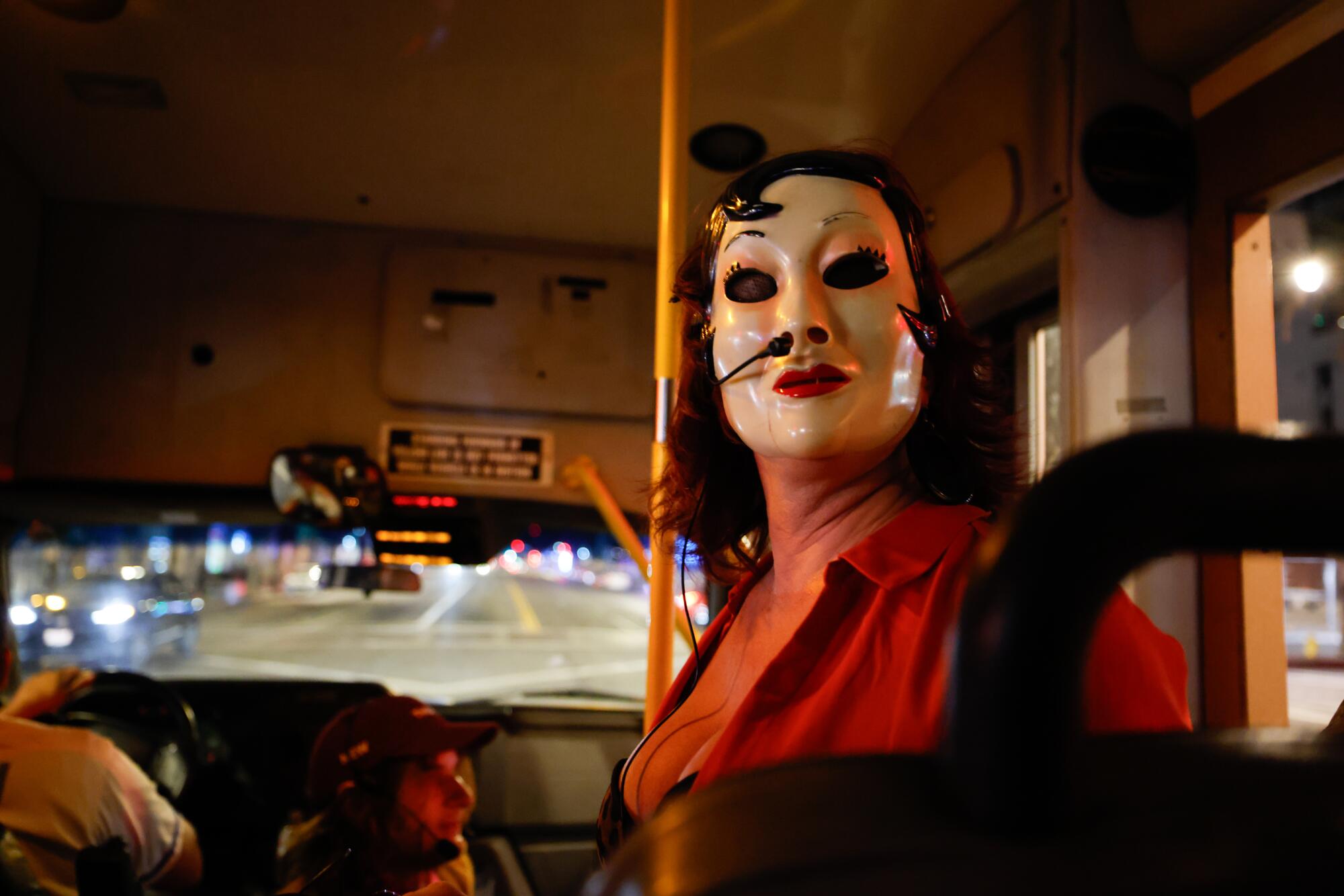 A woman with a mask sits in a bus. 