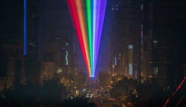 A rainbow of laser lights shines down San Francisco's Market Street at night.