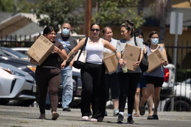 Residents affected by the Boyle Heights warehouse fire walk home with air purifiers, canned food and masks following an event hosted by Via Care Community Health Center at Our Lady of Victory Catholic Church in Los Angeles on Tuesday, June 23, 2026. (Photo by Drew A. Kelley, Press-Telegram/SCNG)