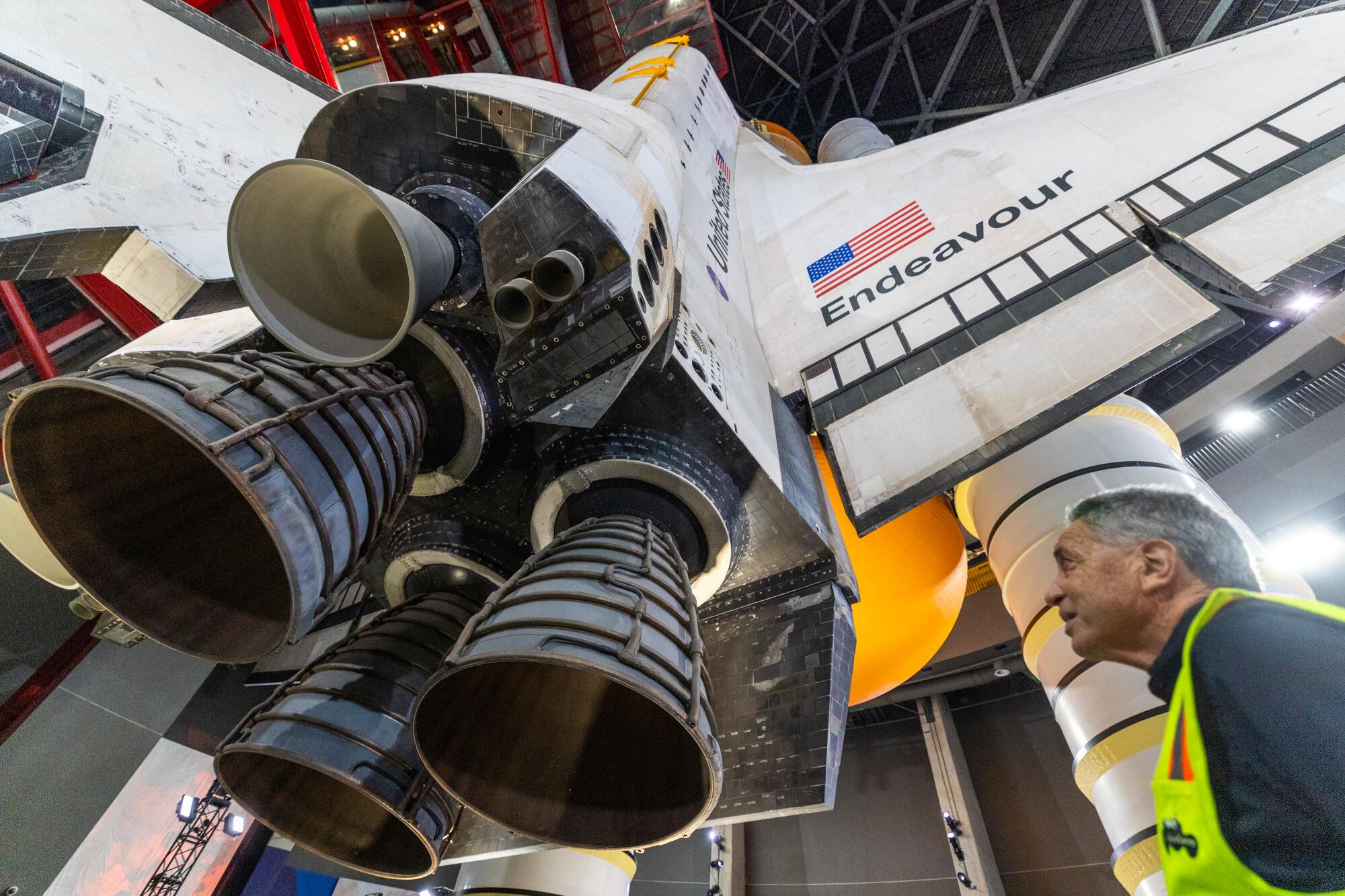 A man stands below the Endeavor space shuttle.