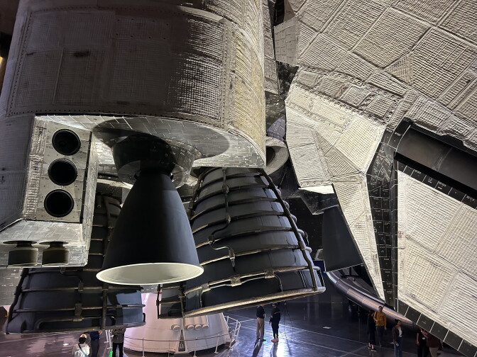 A close up of the bottom of a space shuttle. Three engines are on the left next to the rear of the orbiter.
