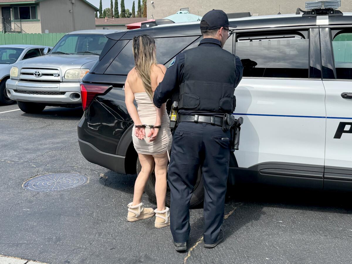 A woman in handcuffs next to a police officer