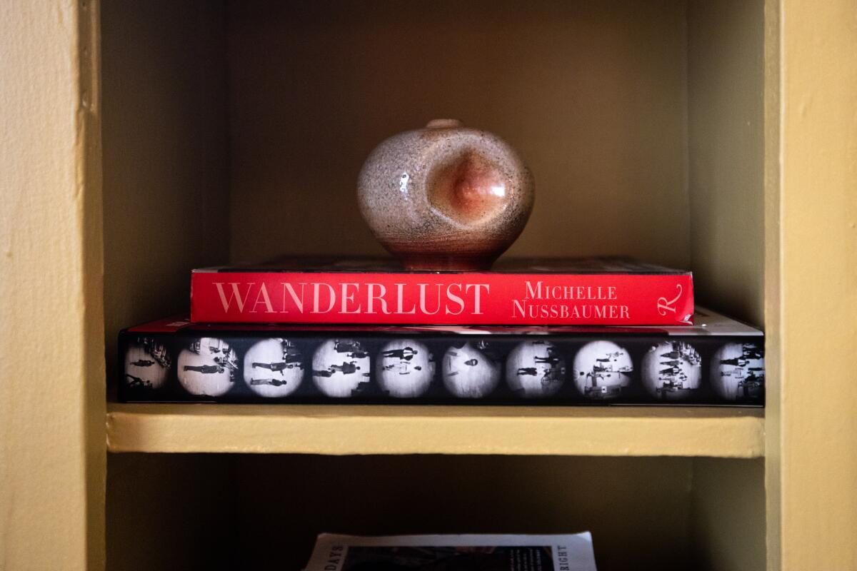 Julio Miranda-Martin fills the bookshelf in his dining room with books and treasures.