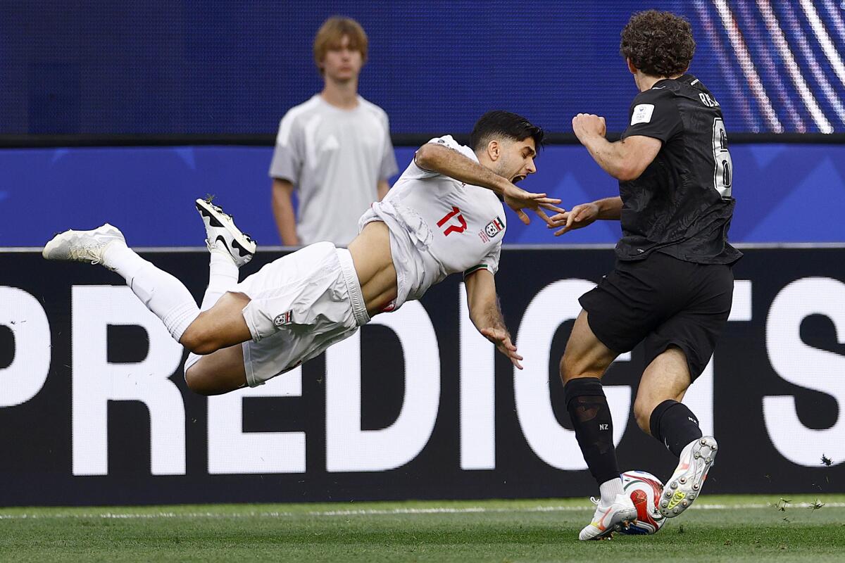 Iran midfielder Aria Yousefi flies into the air after going for the ball against New Zealand midfielder Joe Bell.