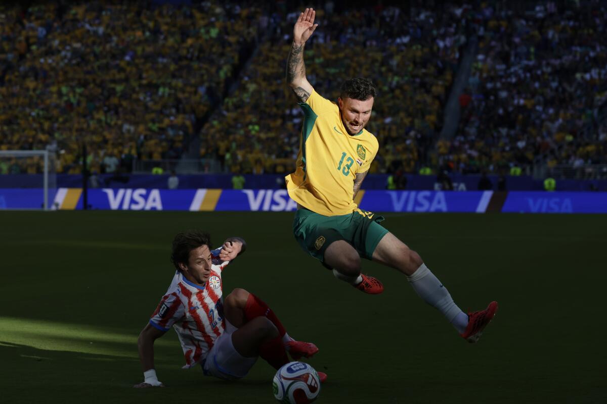 Australia midfielder Aiden O'Neill leaps over Paraguay midfielder Matias Galarza during the first half.