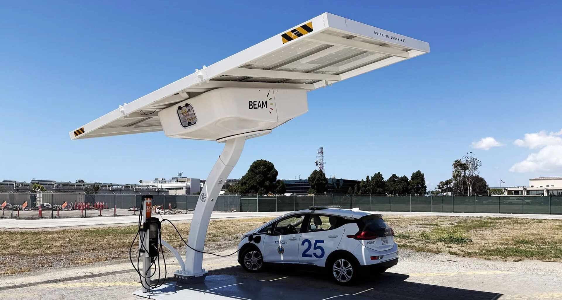 A white electric vehicle charging at a solar-powered station.