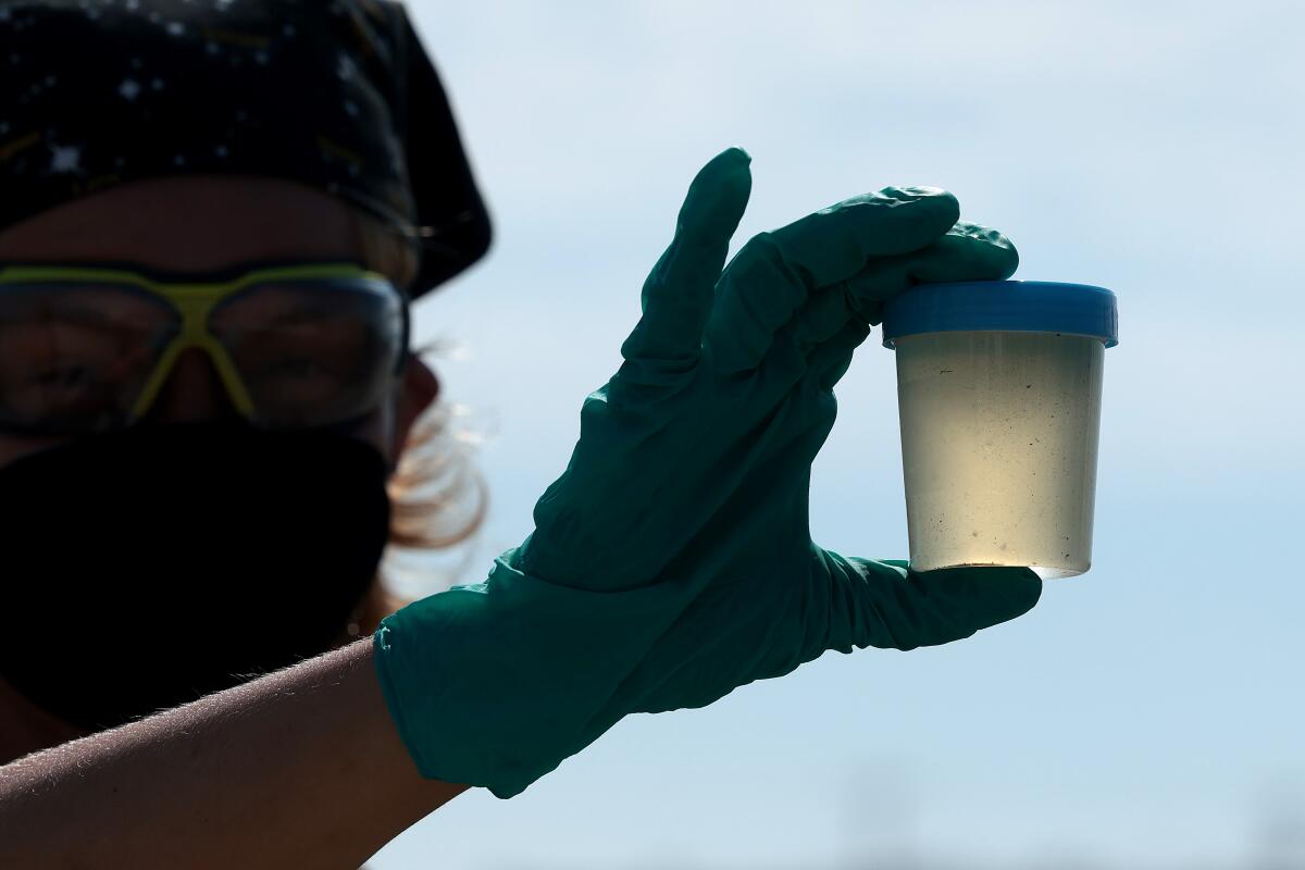Casey Cooper holds a water sample.