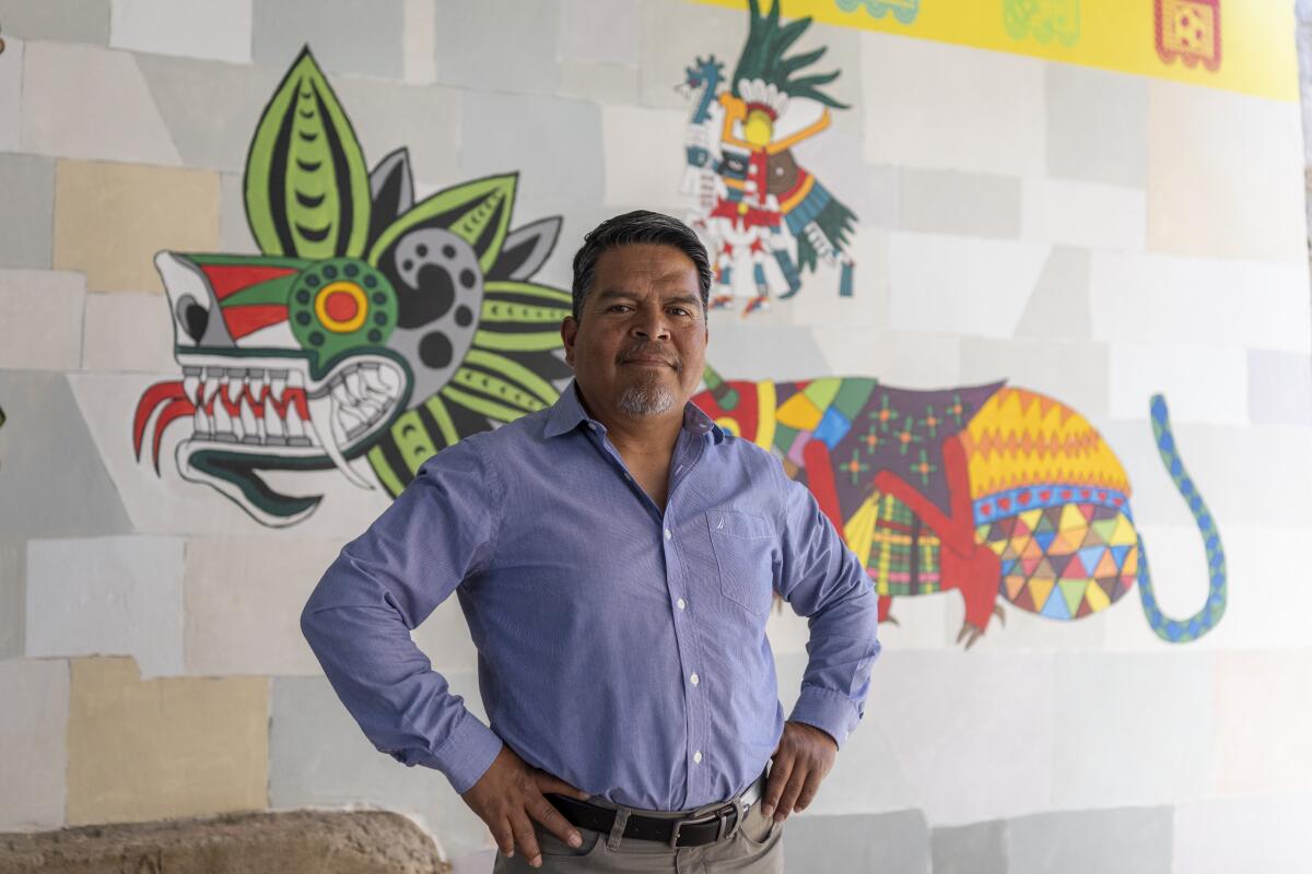 Juan de Dios Ramirez Gonzalez, a principal at the elementary school stands in front of part of the mural