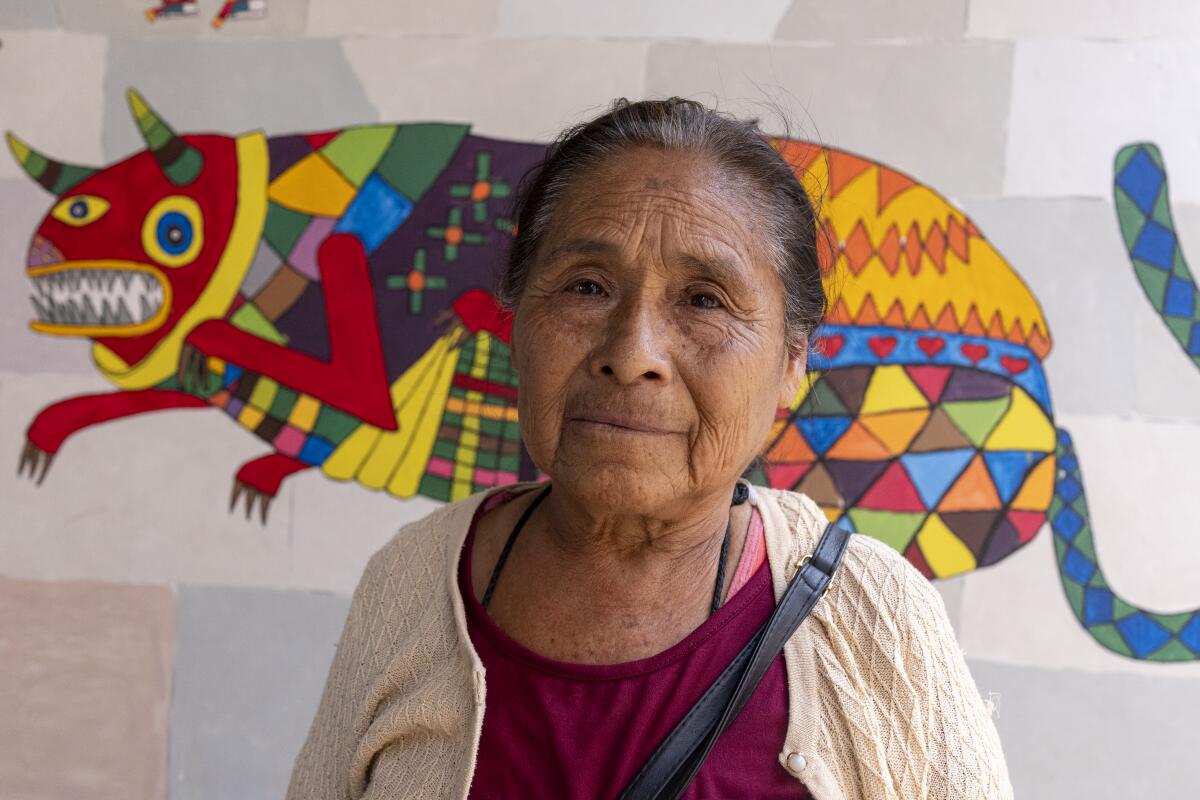 Felipa Sanchez Cruz stands in front of an Alebrijes that she helped paint at elementary school Luis Donaldo Colosio Murrieta.