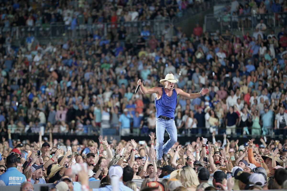A country music artist performs onstage in a fully packed arena