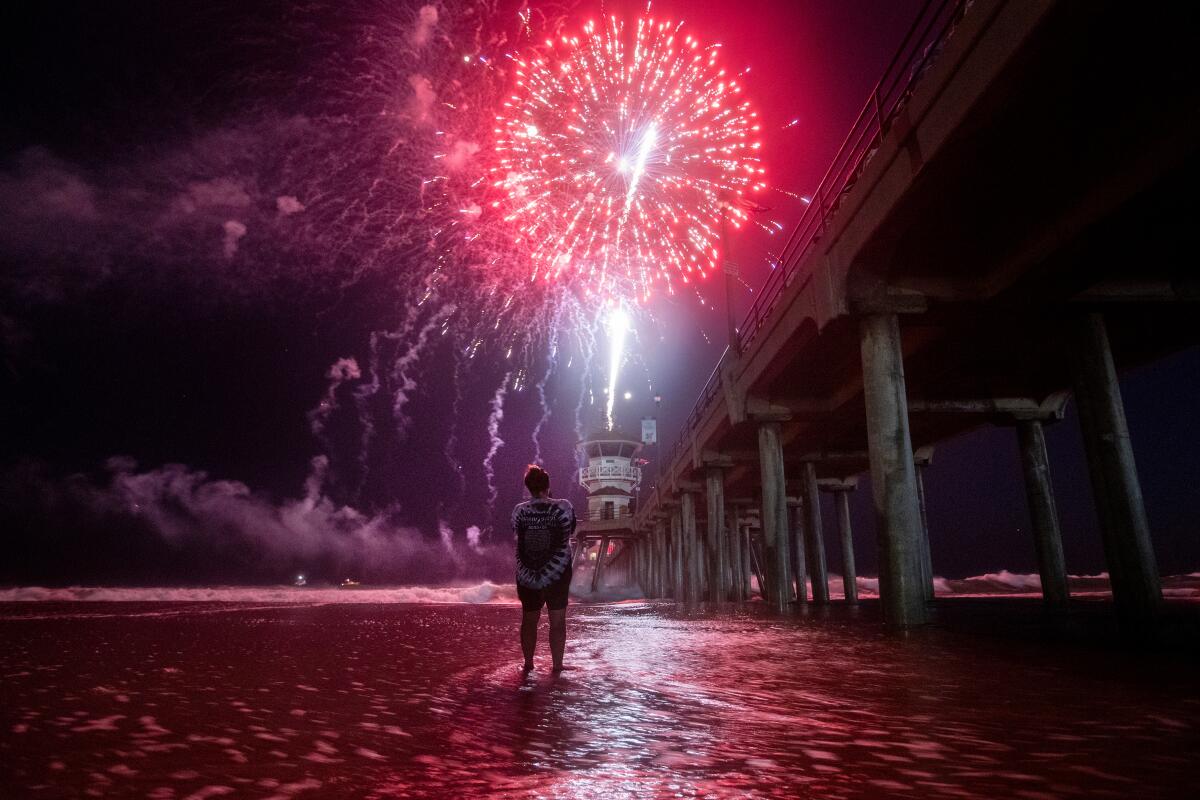  A person wades into the water for a closer look at the fireworks celebration in Huntington Beach on July 4, 2023.