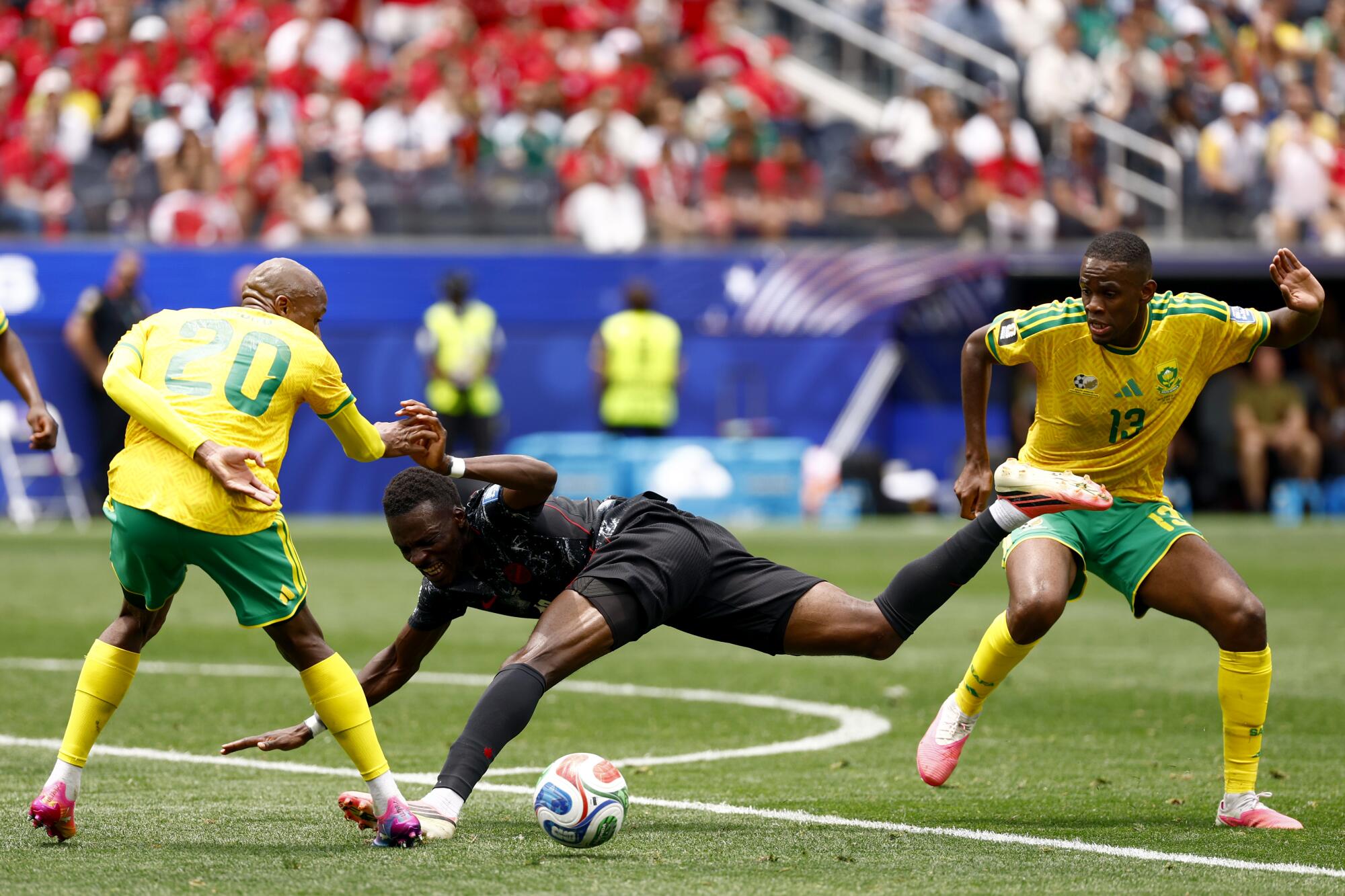 Canada's Tani Oluwaseyi, center, gets caught between South Africa's Khuliso Mudau (20) and Sphephelo Sithole.