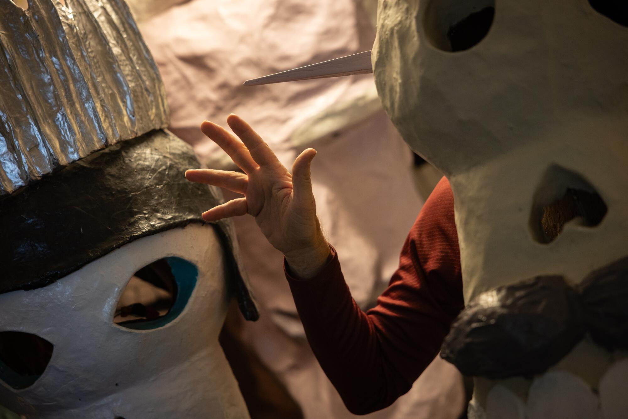 A man poses in a papier mache mask