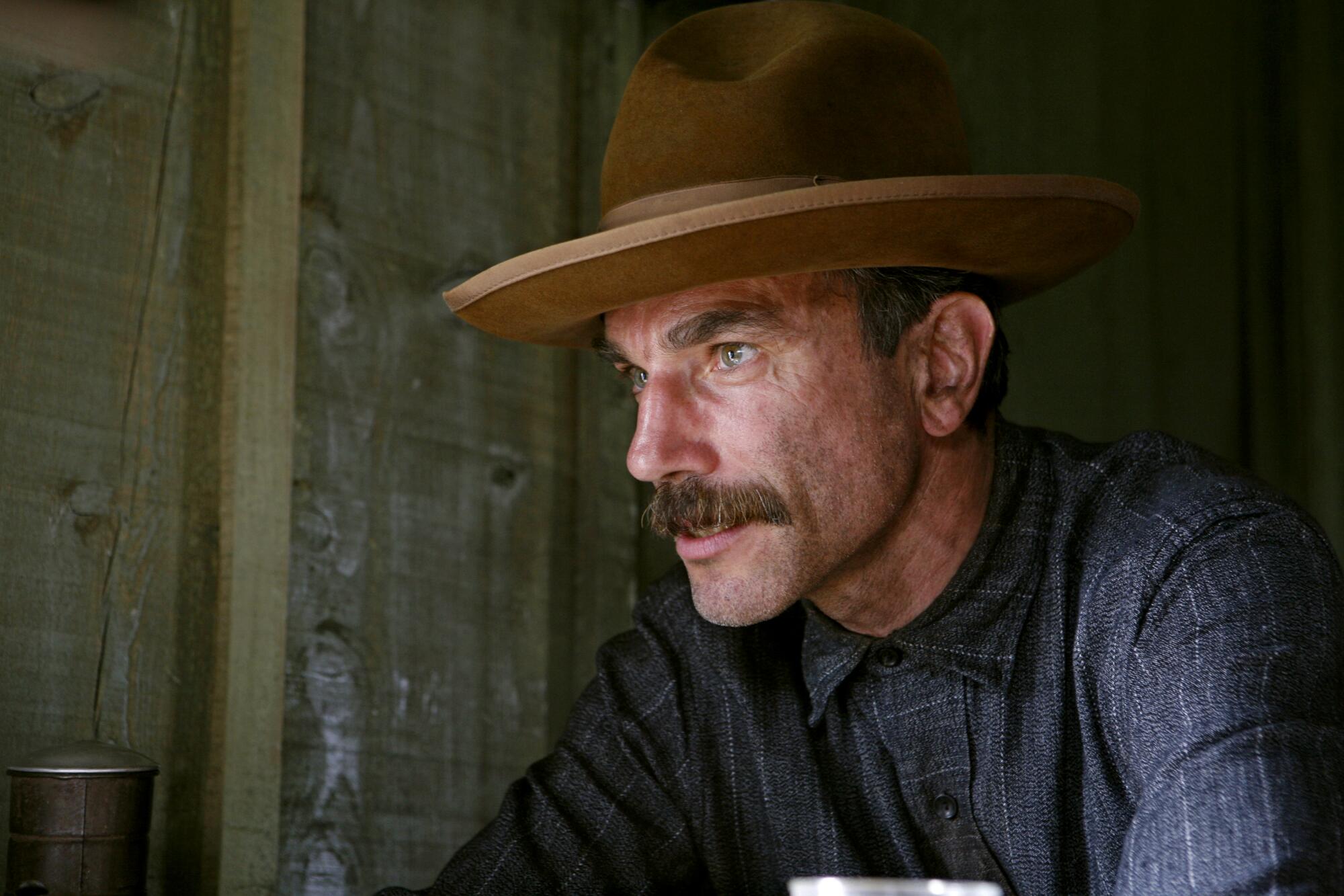 A man in a brown hat stares ahead with determination.