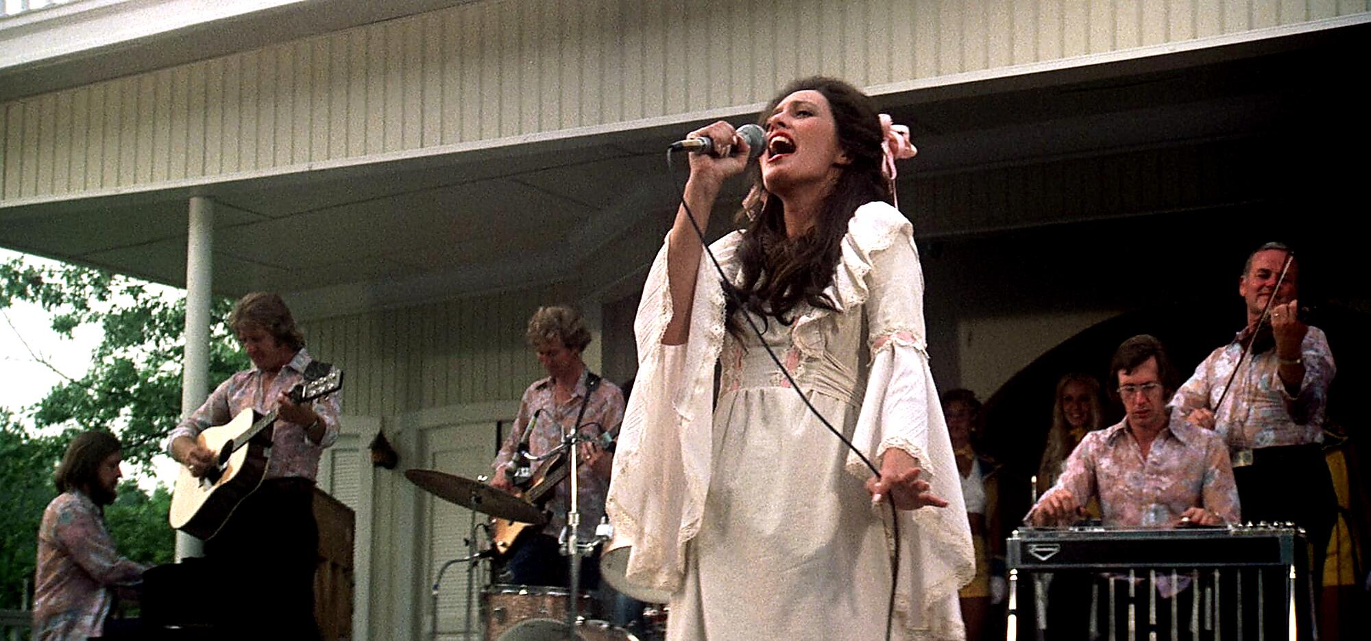 A woman in white sings at a country music concert.