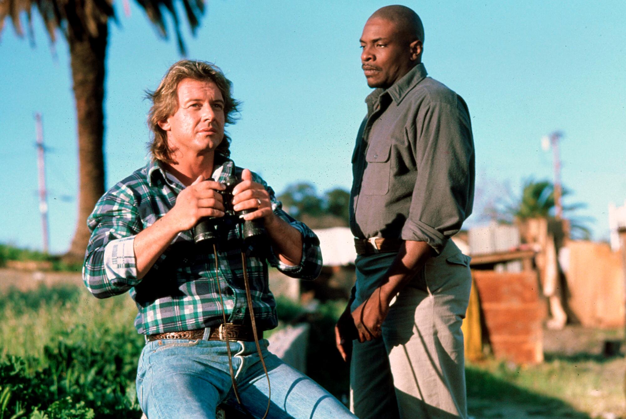 Two men sit in an outdoor tent camp in Los Angeles.