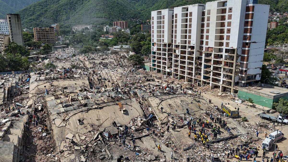 Rescue workers stand on collapsed buildings amid damaged ones along the coast in Caraballeda.