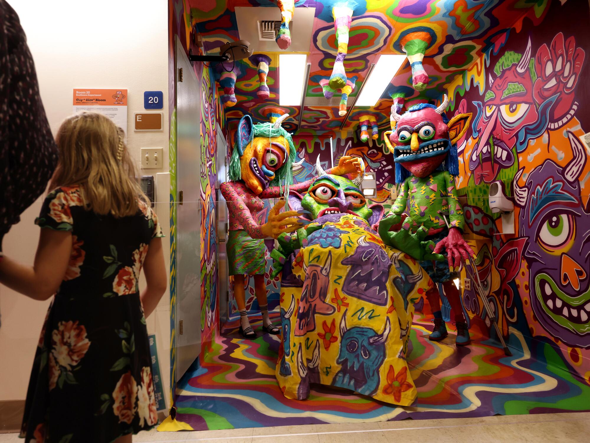 A child looks into a room filled with colorful monstrous figures.