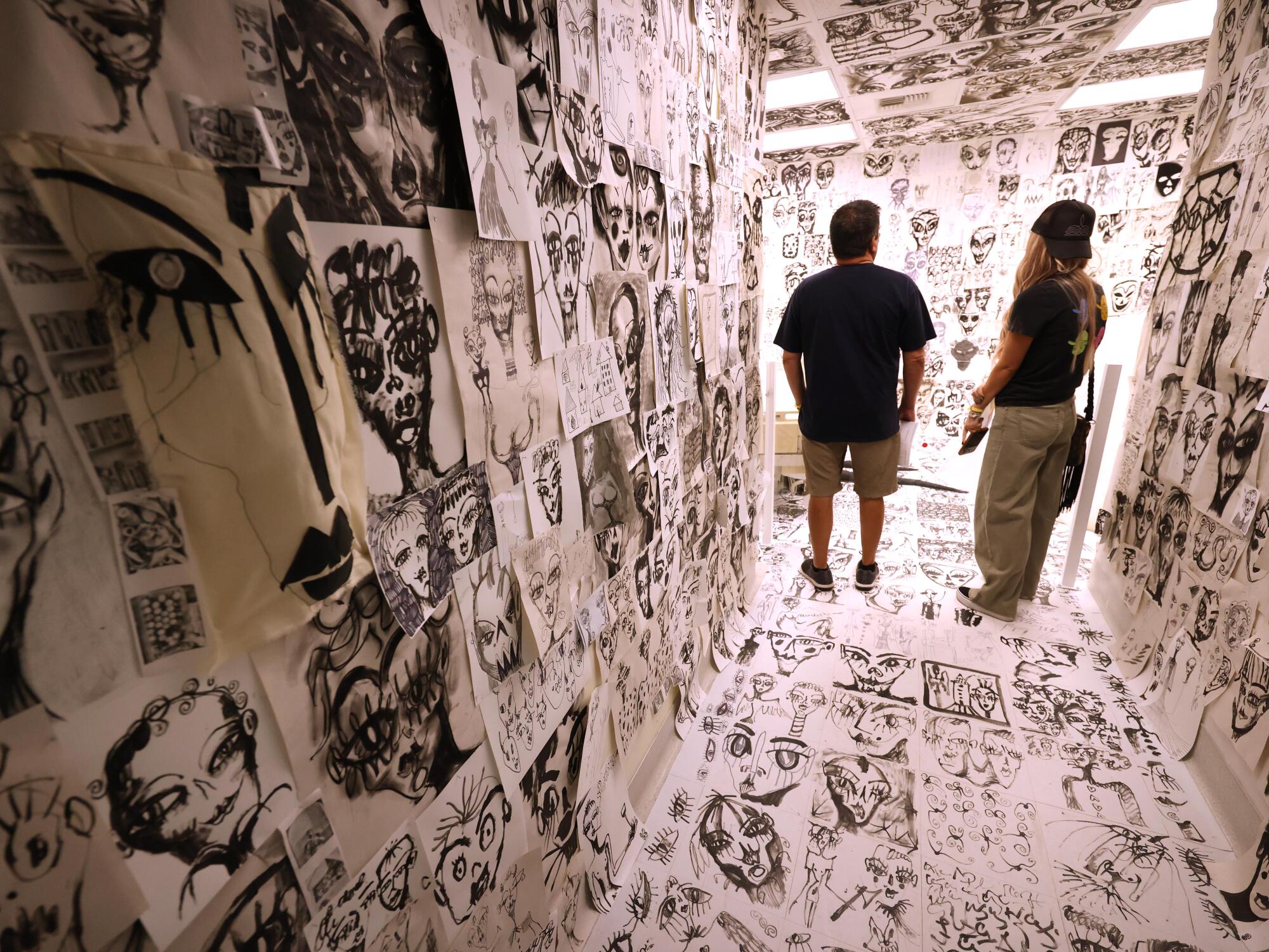 Two people stand in a hallway filled with black-and-white images.