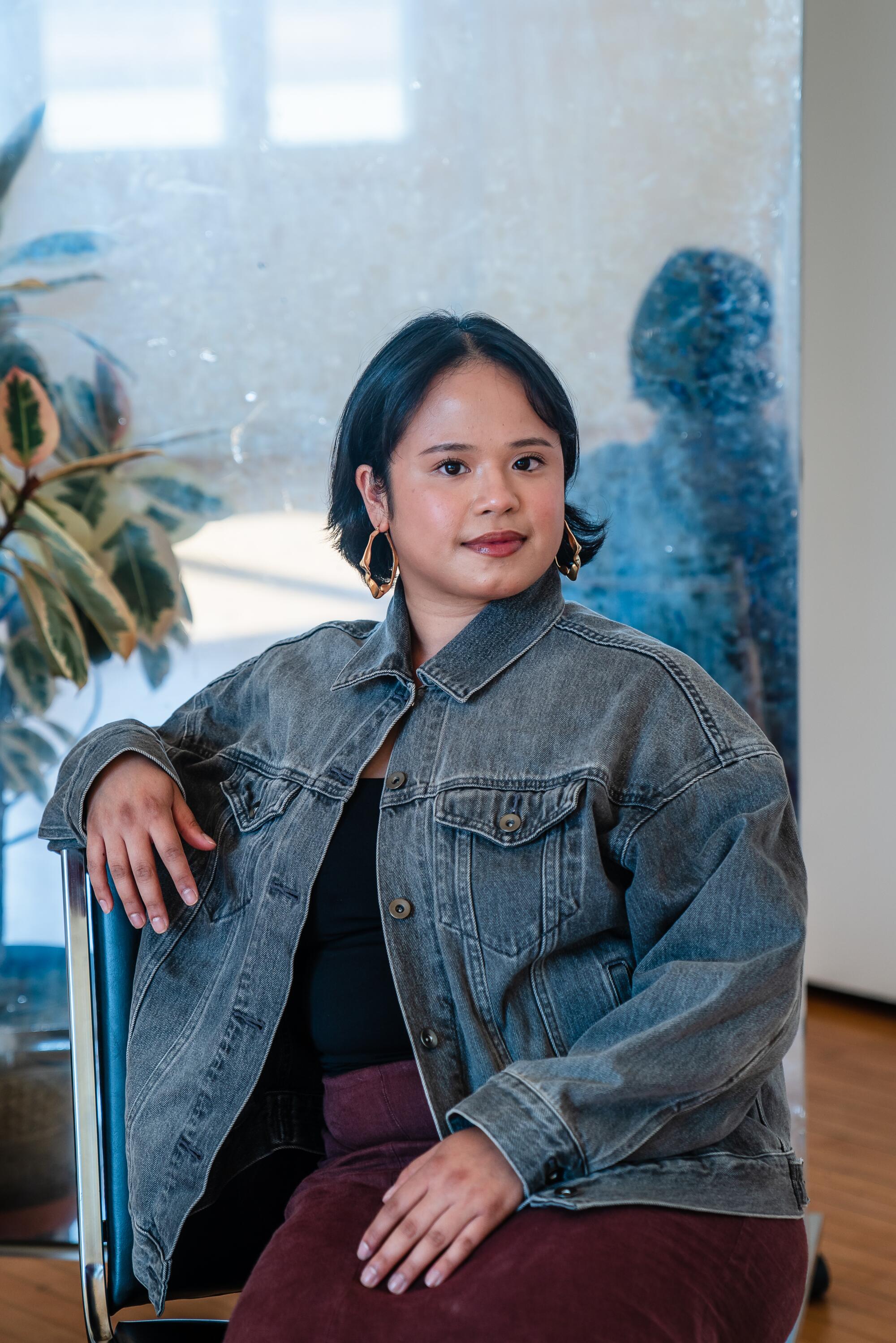 Adie San Diego sits on a chair in a studio. 