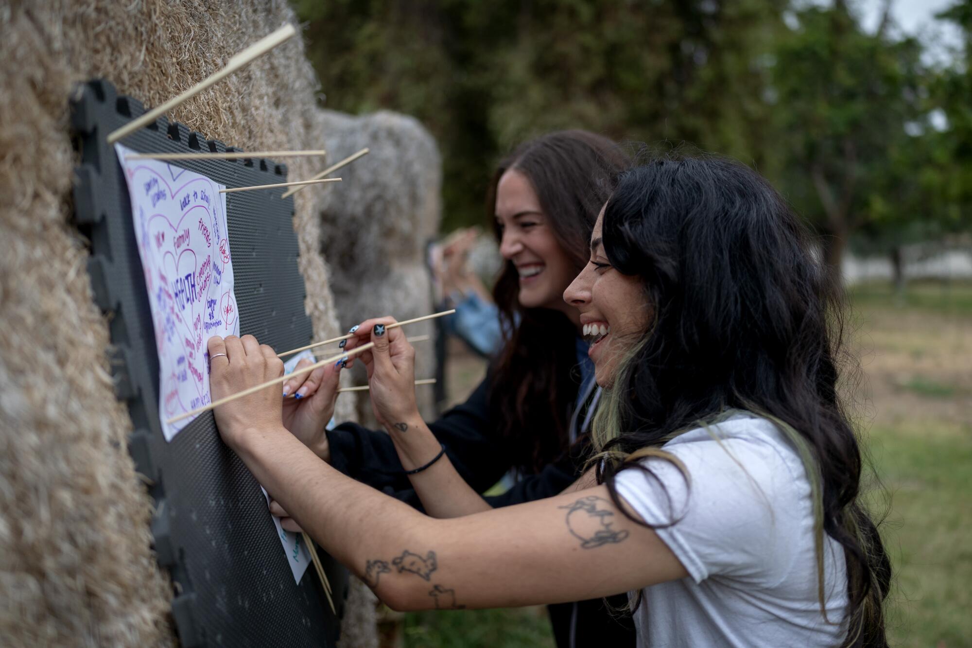 Kati Lee, right, and Tristan Gonzales affix their targets during a Mindful Archery class.