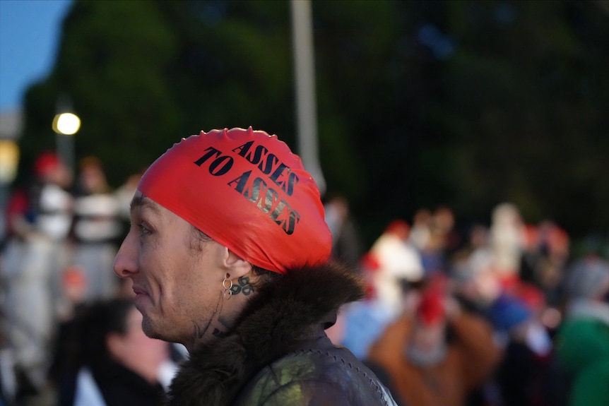 A person wearing a red swimming cap with the words "Asses to asses" printed on it.