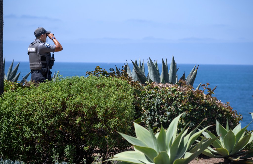 A park ranger scans the horizon with binoculars on Laguna Beach.