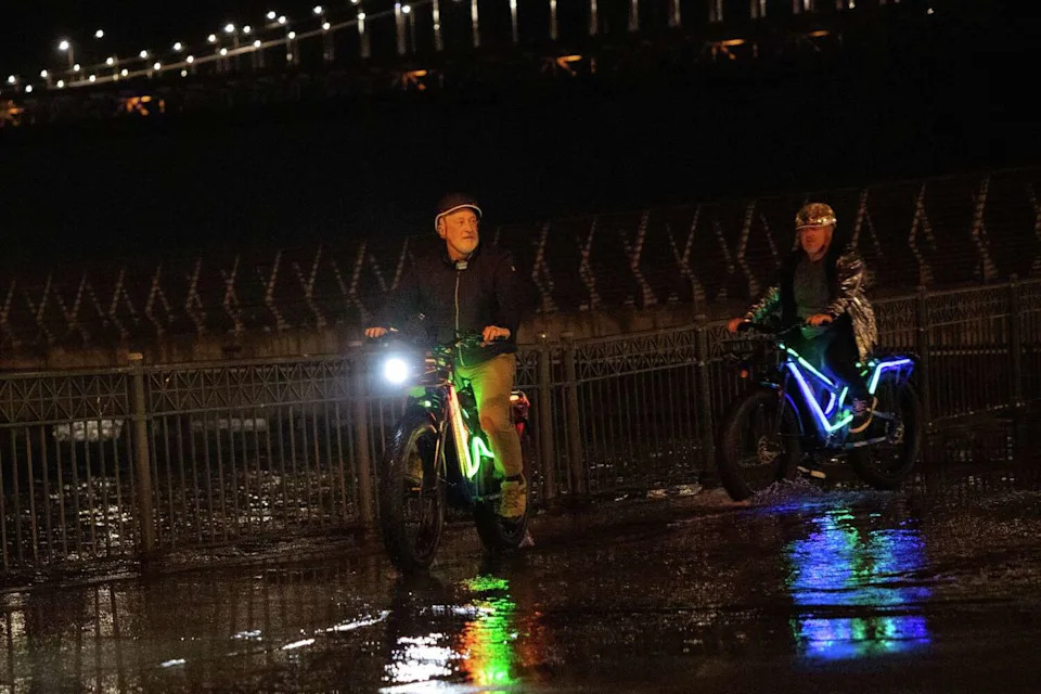 Bicyclists ride through overflowing water at Pier 14 on the Embarcadero during what was forecast to be the highest summer tides on record in San Francisco. (Manuel Orbegozo/For the S.F. Chronicle)