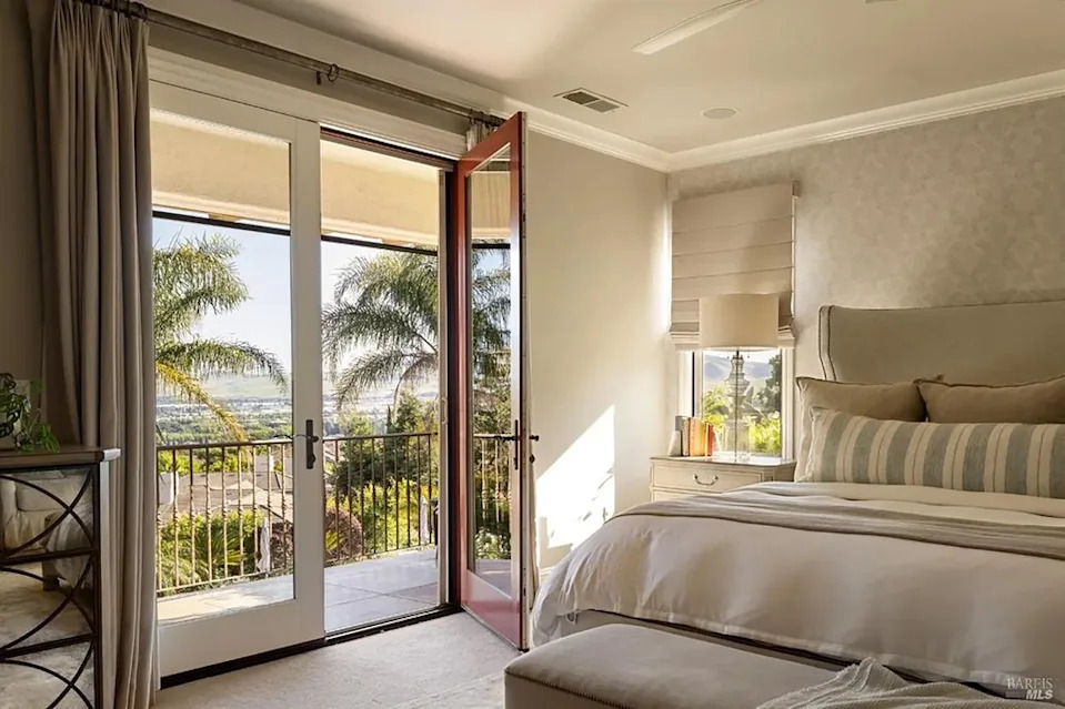 Bright master bedroom with open balcony doors showcasing scenic valley views