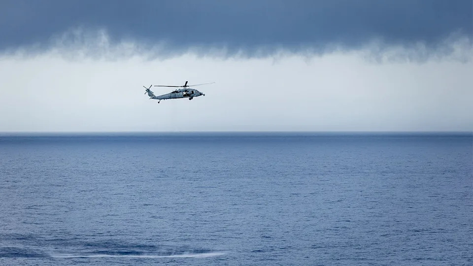 US Navy helicopter flies above ocean