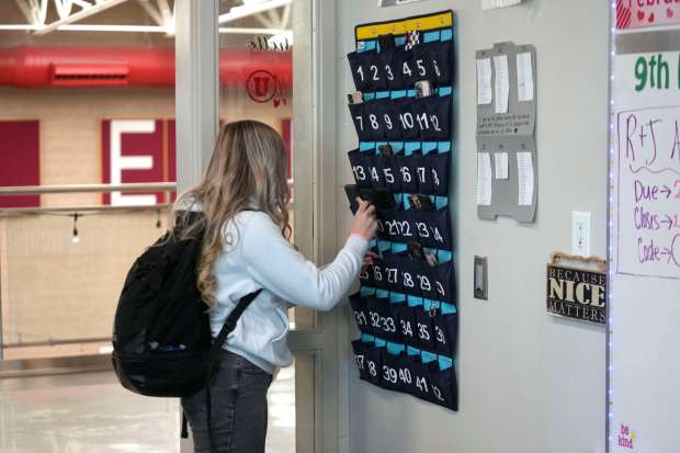 FILE - A ninth grader places her cellphone in to a phone holder as she enters class at Delta High School, Friday, Feb. 23, 2024, in Delta, Utah. (AP Photo/Rick Bowmer, File)