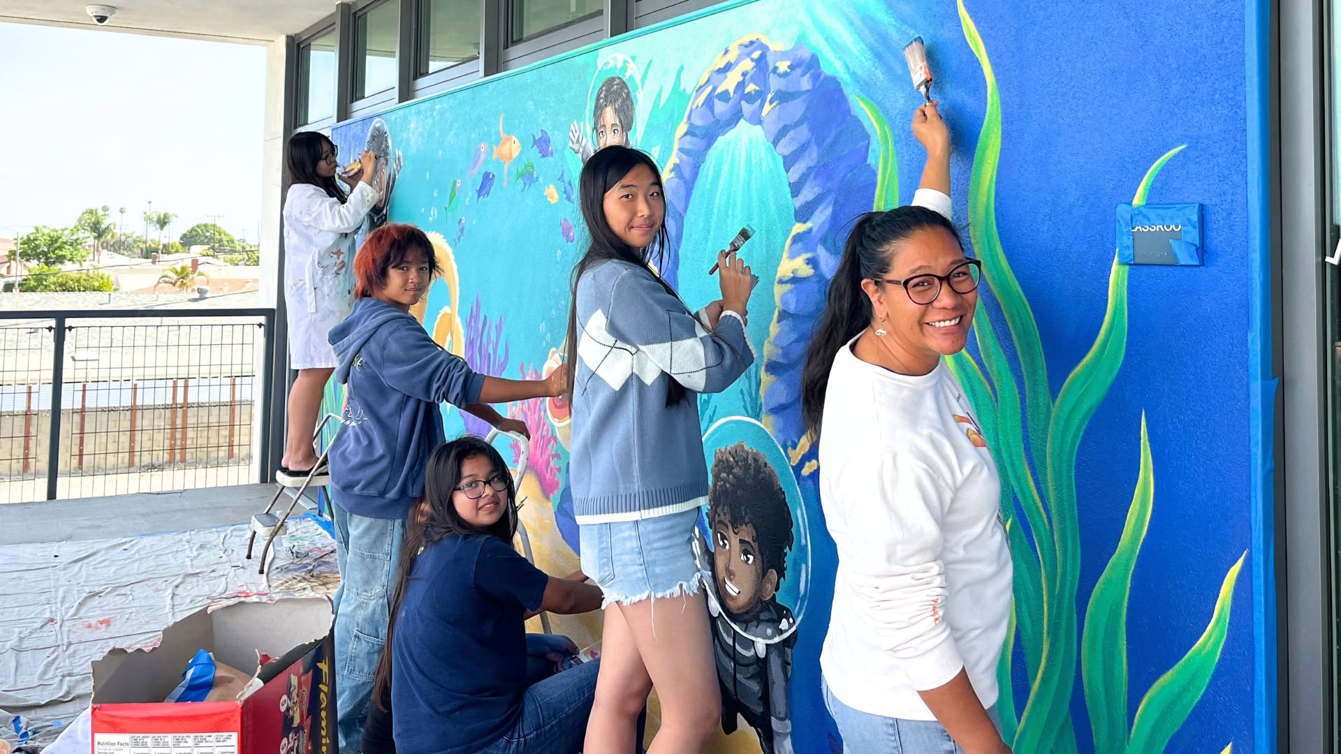 Students and a teacher work on a mural celebrating the ecosystems of the Bolsa Chica Wetlands at Warner Middle School.