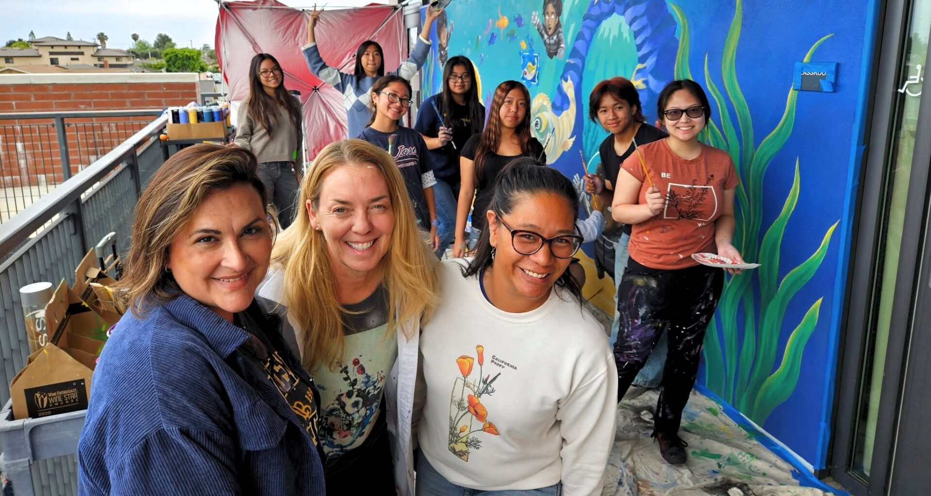 Painters from Warner Middle School and Westminster High School pose for a photo while working on a mural depicting the ecosystems of the Bolsa Chica Wetlands.