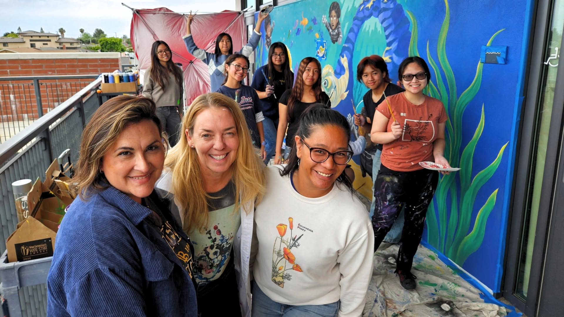 Painters from Warner Middle School and Westminster High School pose for a photo while working on a mural depicting the ecosystems of the Bolsa Chica Wetlands.