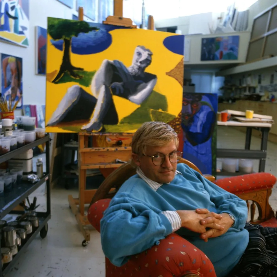Portrait of English painter David Hockney, dressed in a light blue sweatshirt and tan trousers, as he sits on a chaise longue in his home, Los Angeles, California, 1987. (Photo by Anthony Barboza/Getty Images)