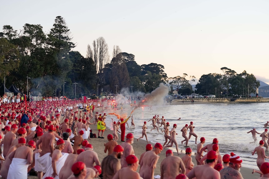 Crowd of swimmers prepare to enter the water for Dark Mofo's 2026 Nude Solstice Swim