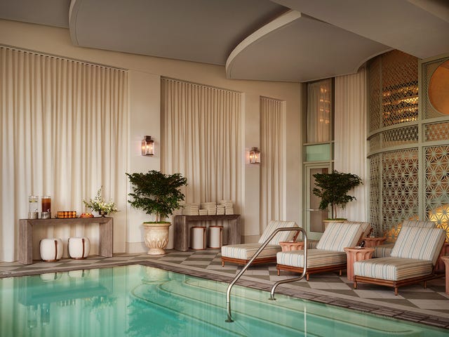 Luxurious indoor pool area with lounge chairs and potted plants. Luxurious indoor pool area with lounge chairs and potted plants.